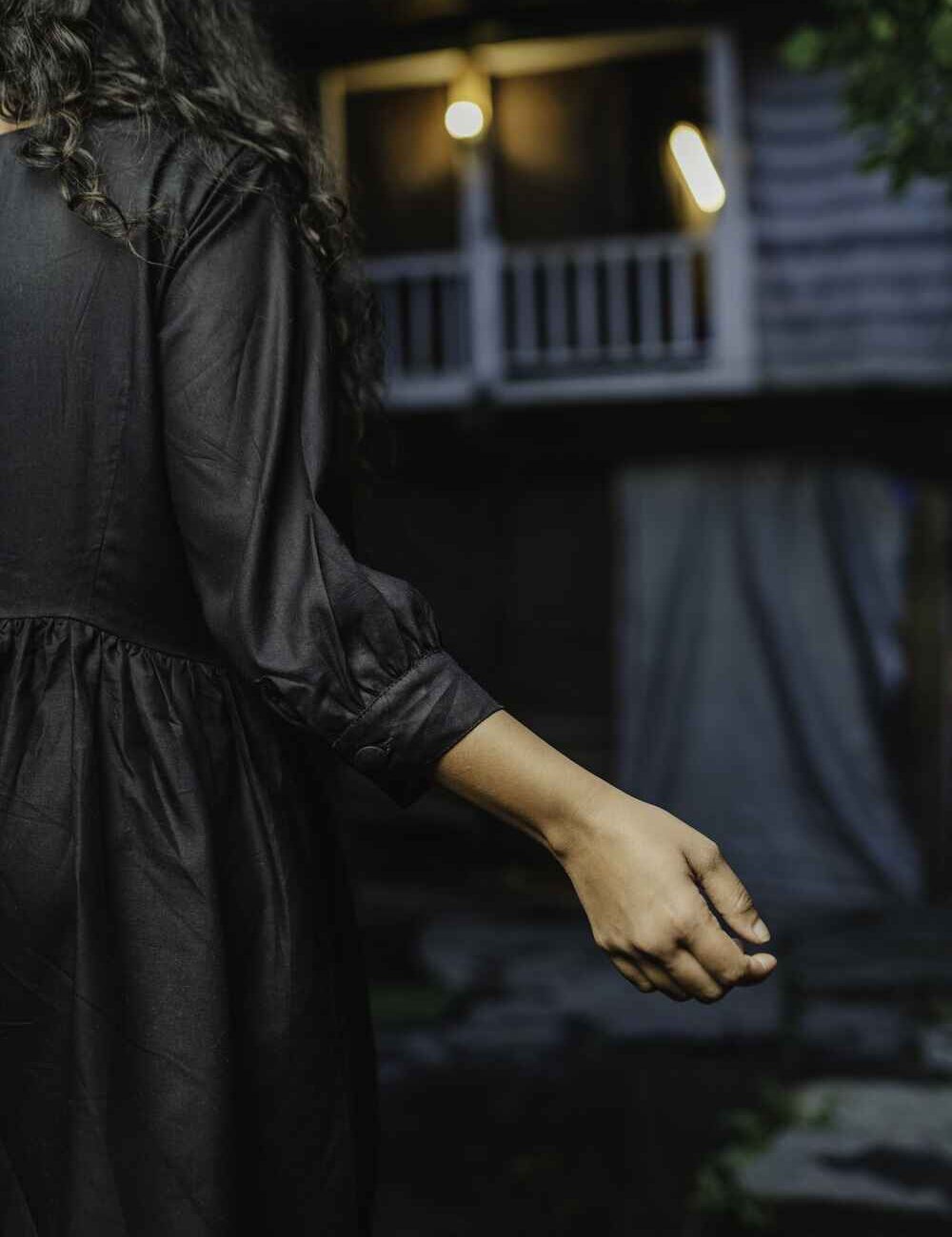 Model in a comfy black linen-cotton short dress for women with three-quarter sleeves, standing outdoors.