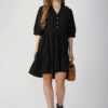 Model wearing a casual black cotton linen tiered dress with a relaxed fit and button-down detai