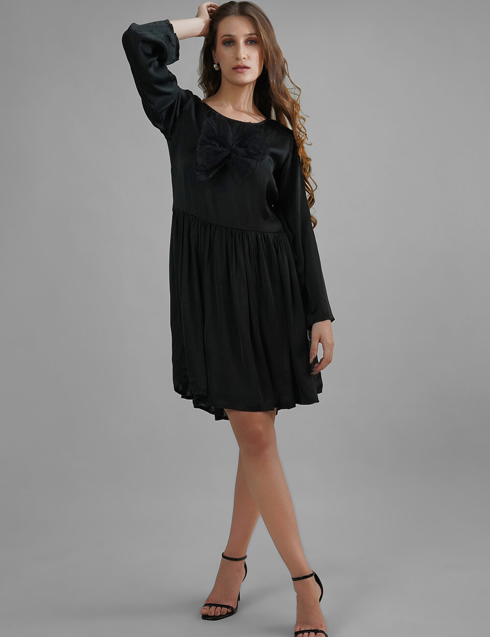 Woman wearing a black satin dress with net butterfly appliqué and gathered skirt