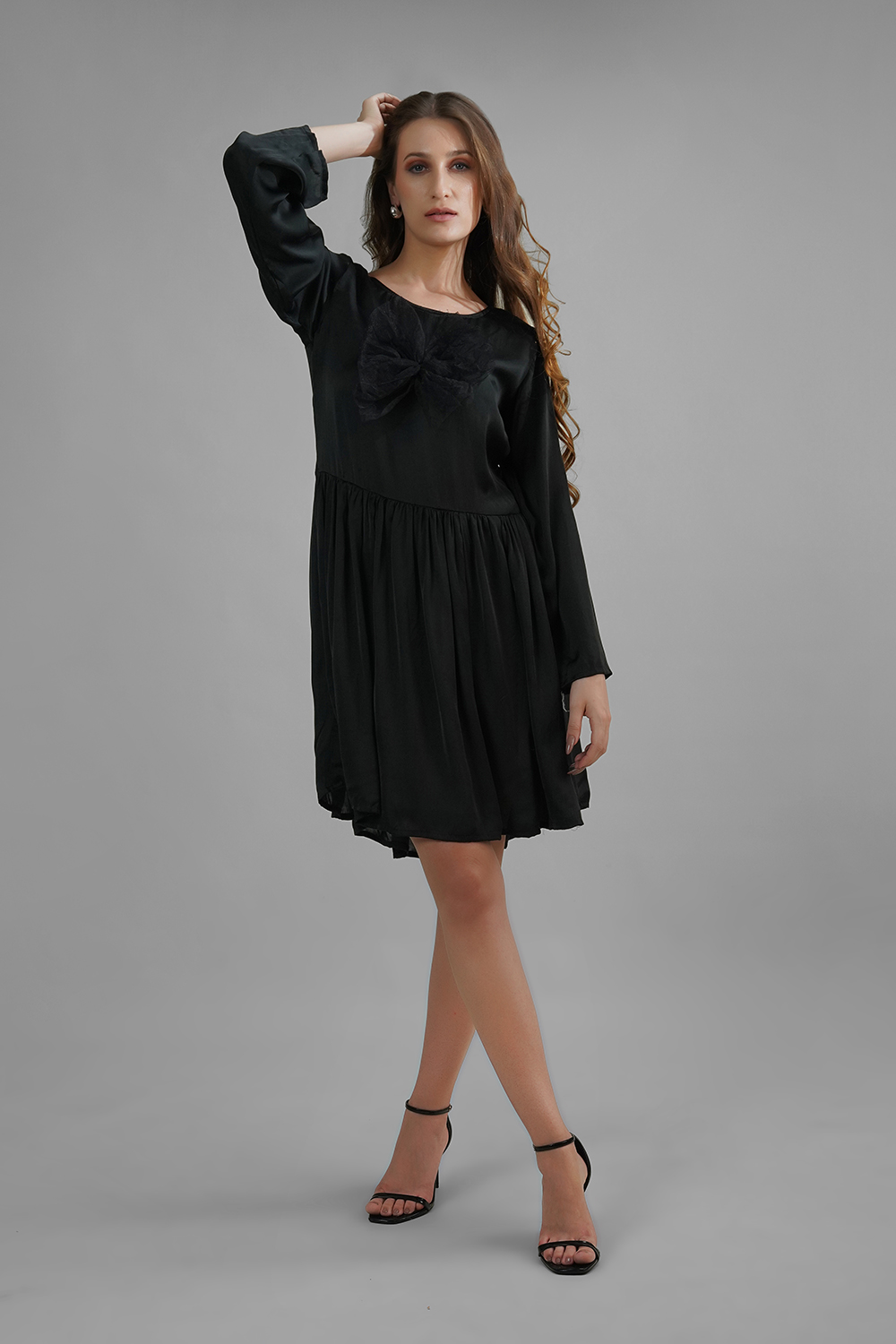 Woman wearing a black satin dress with net butterfly appliqué and gathered skirt