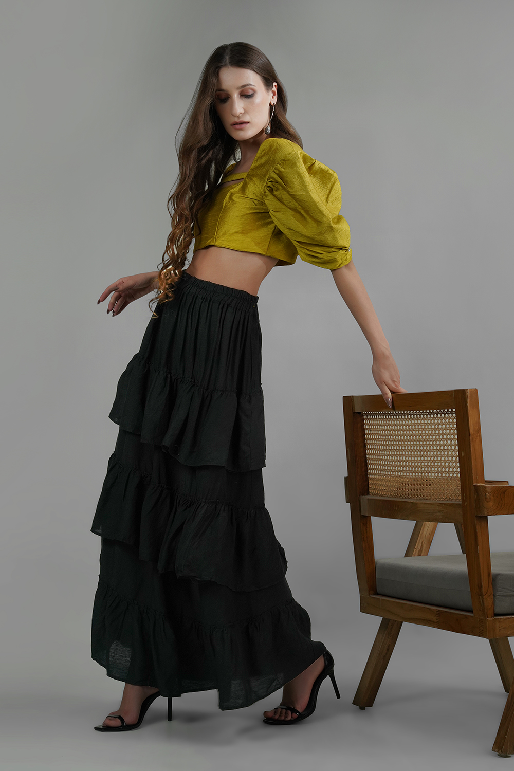 Model wearing a black ruffled ankle-length skirt with tiered panels in cotton linen