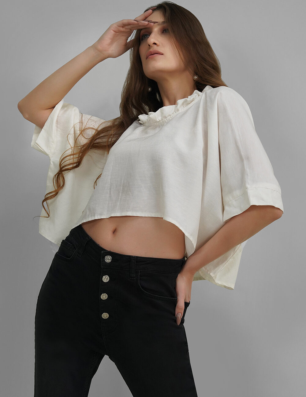 Model in a white oversized crop top with ruffled neck and elbow-length sleeves