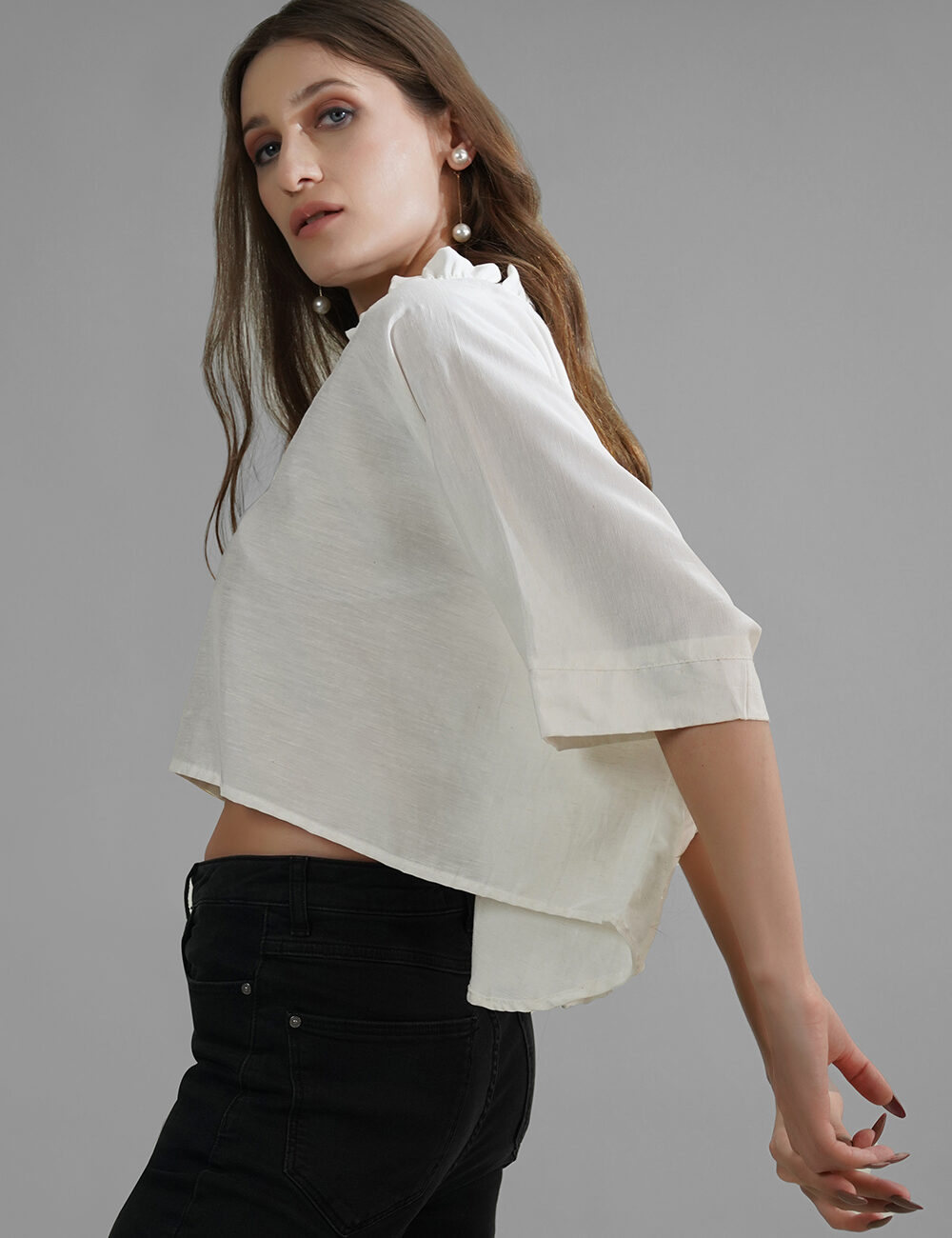 Model in a white oversized crop top with ruffled neck and elbow-length sleeves