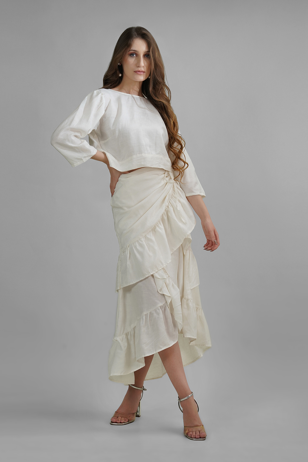 Model wearing a cream cotton-linen crop top with back buttons and 3/4 sleeves