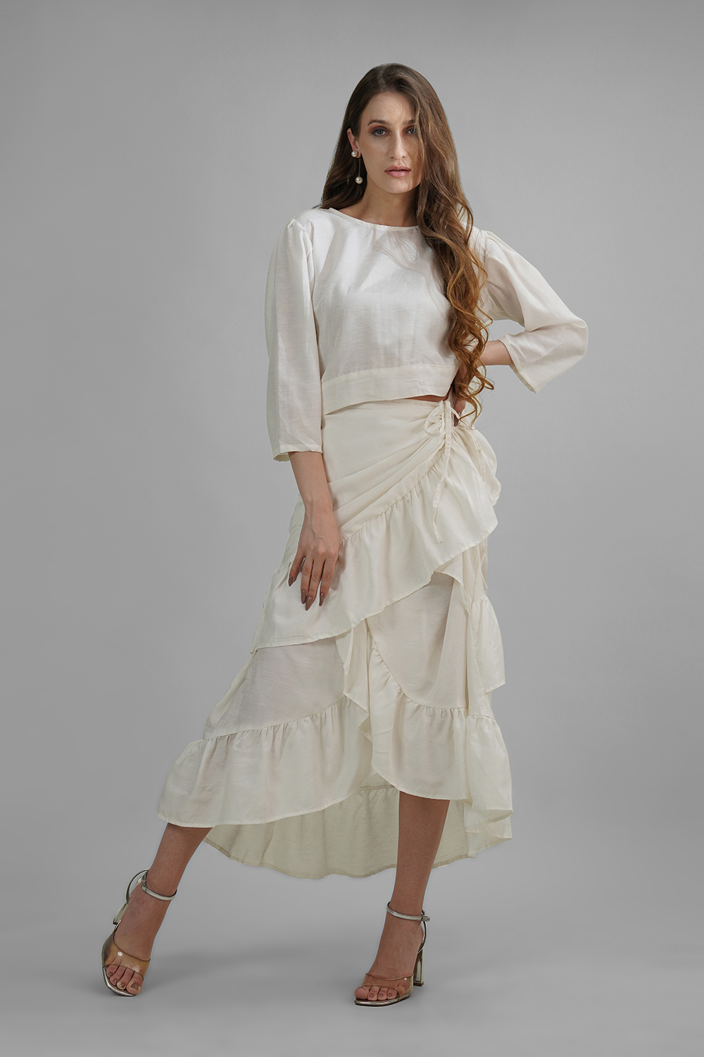 Model in cream high-low ruffled skirt with ruched tie front