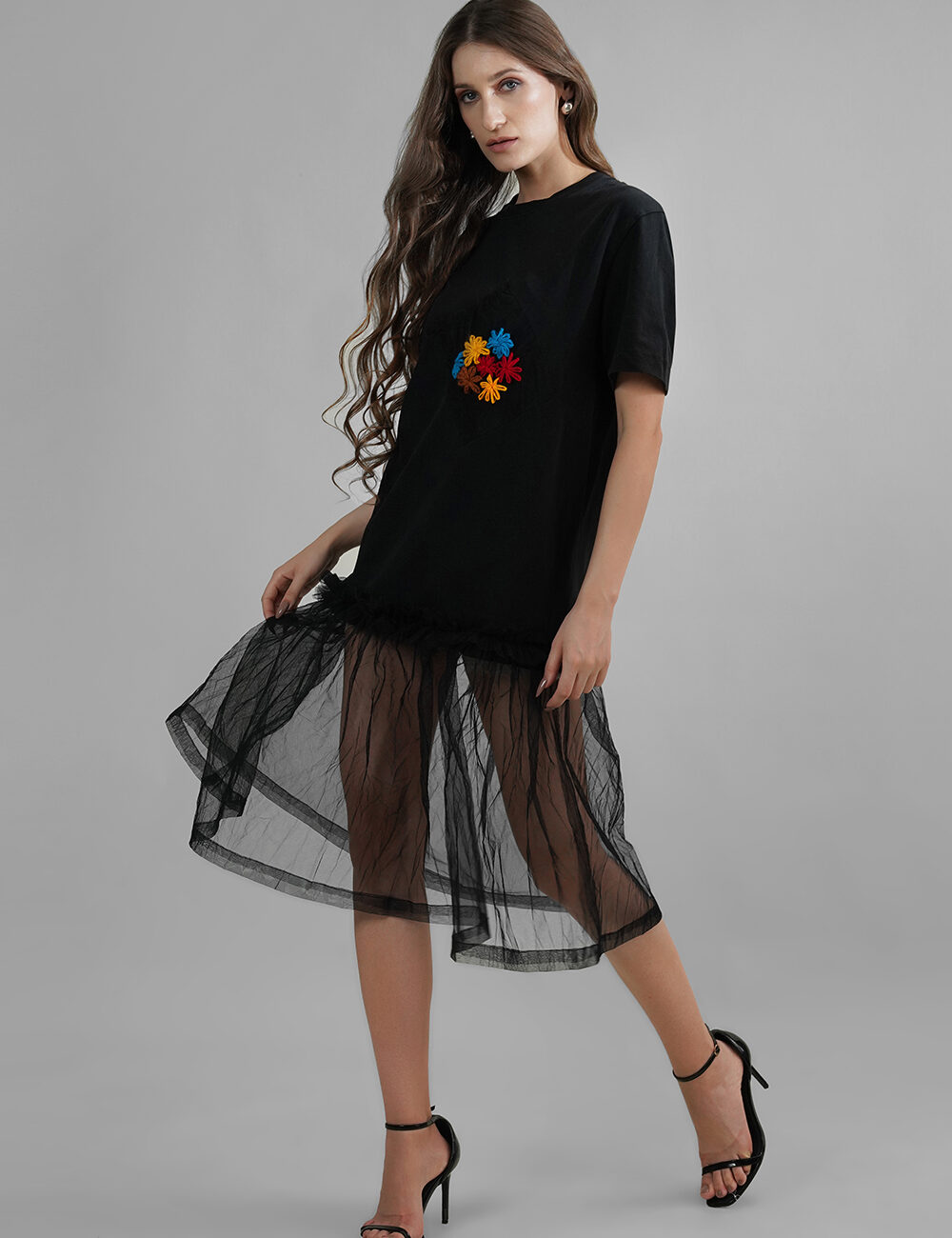 Model wearing oversized black cotton t-shirt with multicolor floral embroidery and butterfly net hem