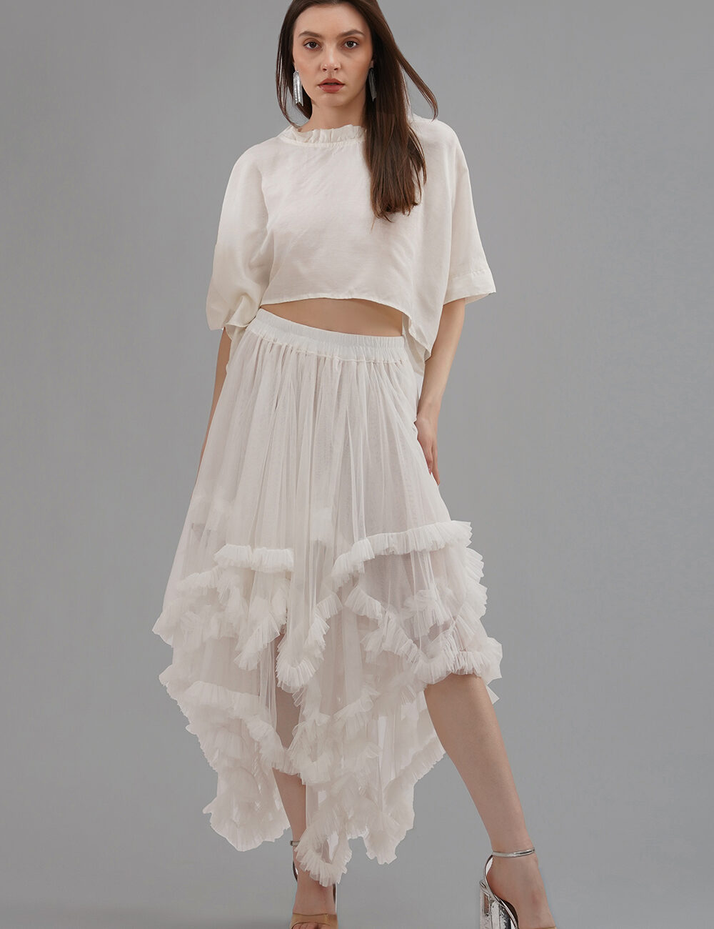 Model wearing a convertible ivory soft net ruffled skirt with lace details