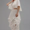 Model wearing a convertible ivory soft net ruffled skirt with lace details